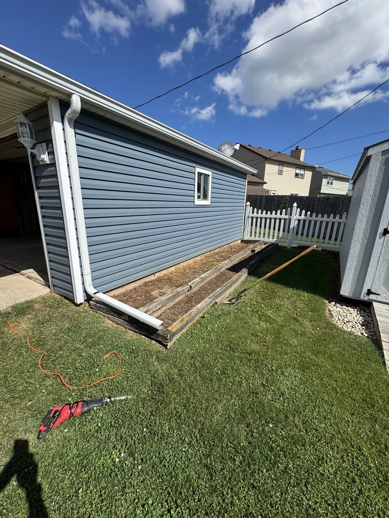 Blue shed with open door in backyard with green grass, residential homes visible in background under blue sky